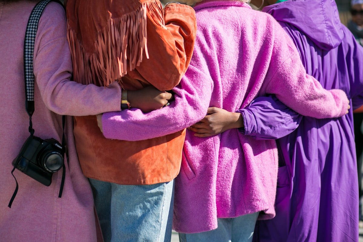 People standing with their arms around each other in bright coats